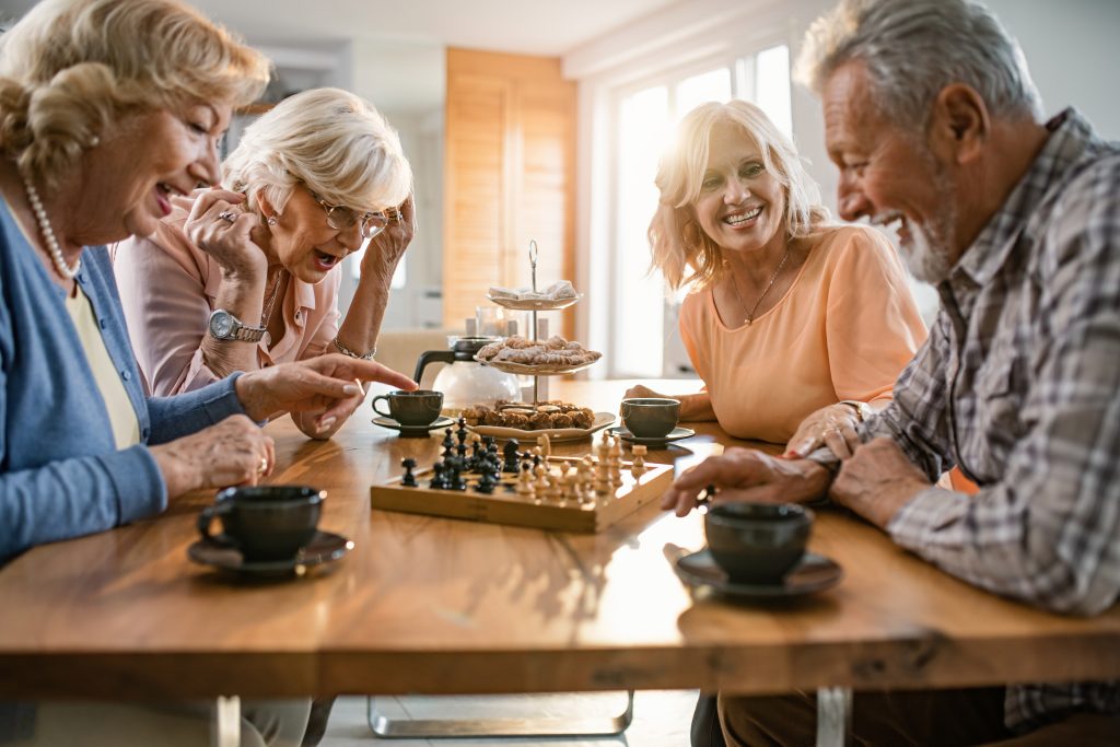 Cheerful selderly having fun while playing chess at home.